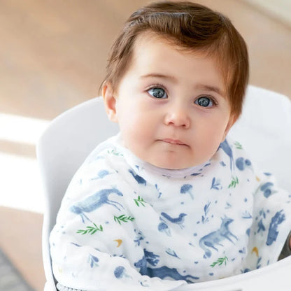 Baby wearing a bib with animal patterns sitting in a high chair.