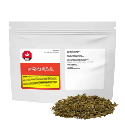 Front view of a white resealable pouch labeled "Fruit Stripez" with a red and yellow warning panel and a small pile of loose green herbal material in front.