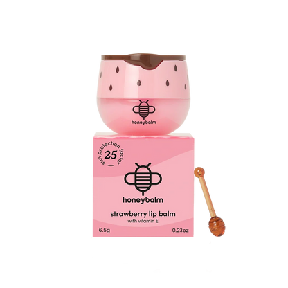 Pink lip balm with strawberry seed design and honeycomb, accompanied by its packaging and a honey stick on a white background.