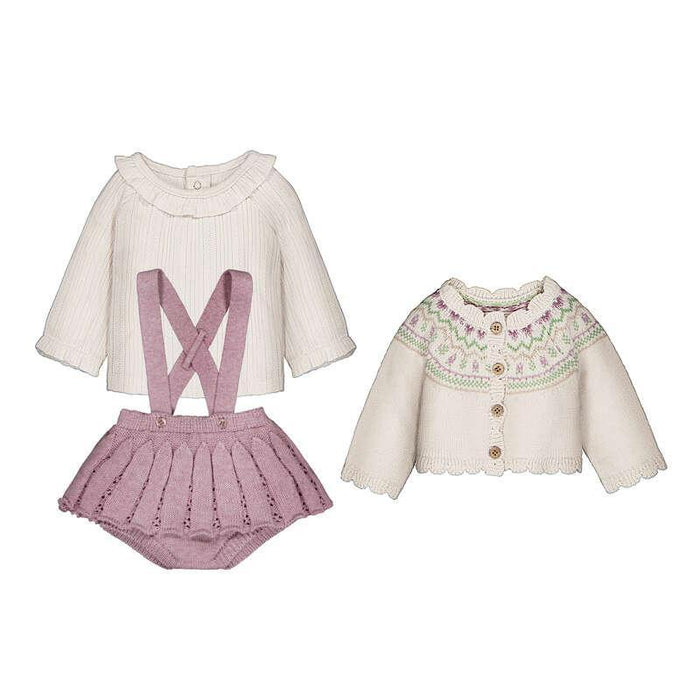 Children's clothing set with white blouse, pink suspenders and skirt, and cream cardigan on a white background
