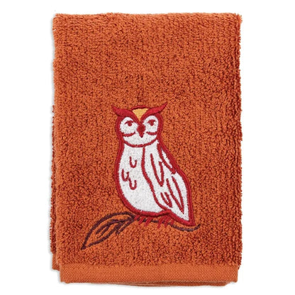 An orange terry cloth towel featuring an embroidered owl on a branch in red, white, and brown, set against a plain white background.