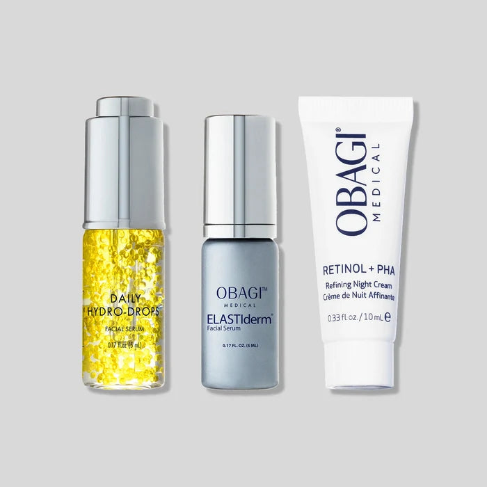 Three OBAGI Medical skincare products arranged side by side on a light gray background: a yellow gel dropper bottle, a silver-toned faceted bottle, and a white retinol night cream tube.
